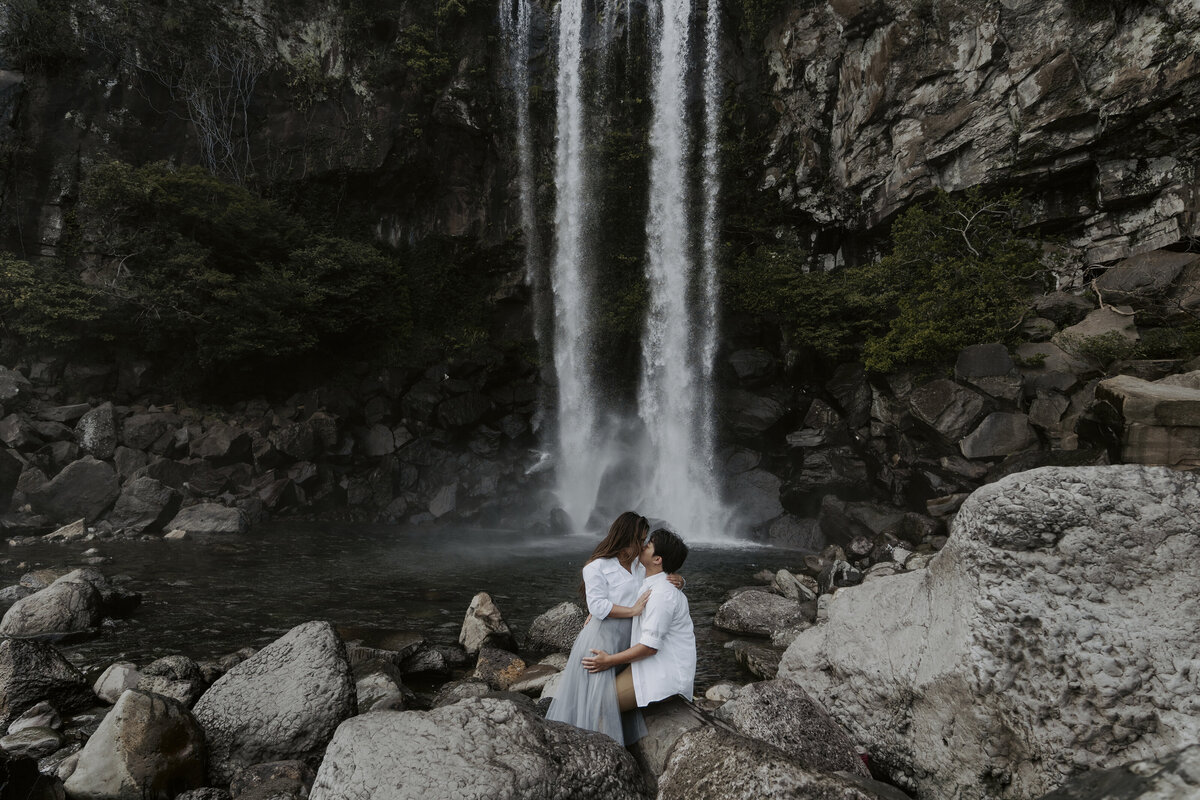 the couple kissing in front of the waterfall in jeju island