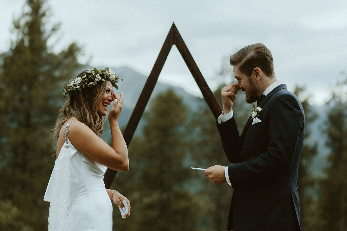 Bride and groom smiling and tearing up at their stunning outdoor wedding ceremony, captured by Tim & Court Photo and Film, joyful and adventurous wedding photographer and videographer in Calgary, Alberta. Featured on the Bronte Bride Vendor Guide.