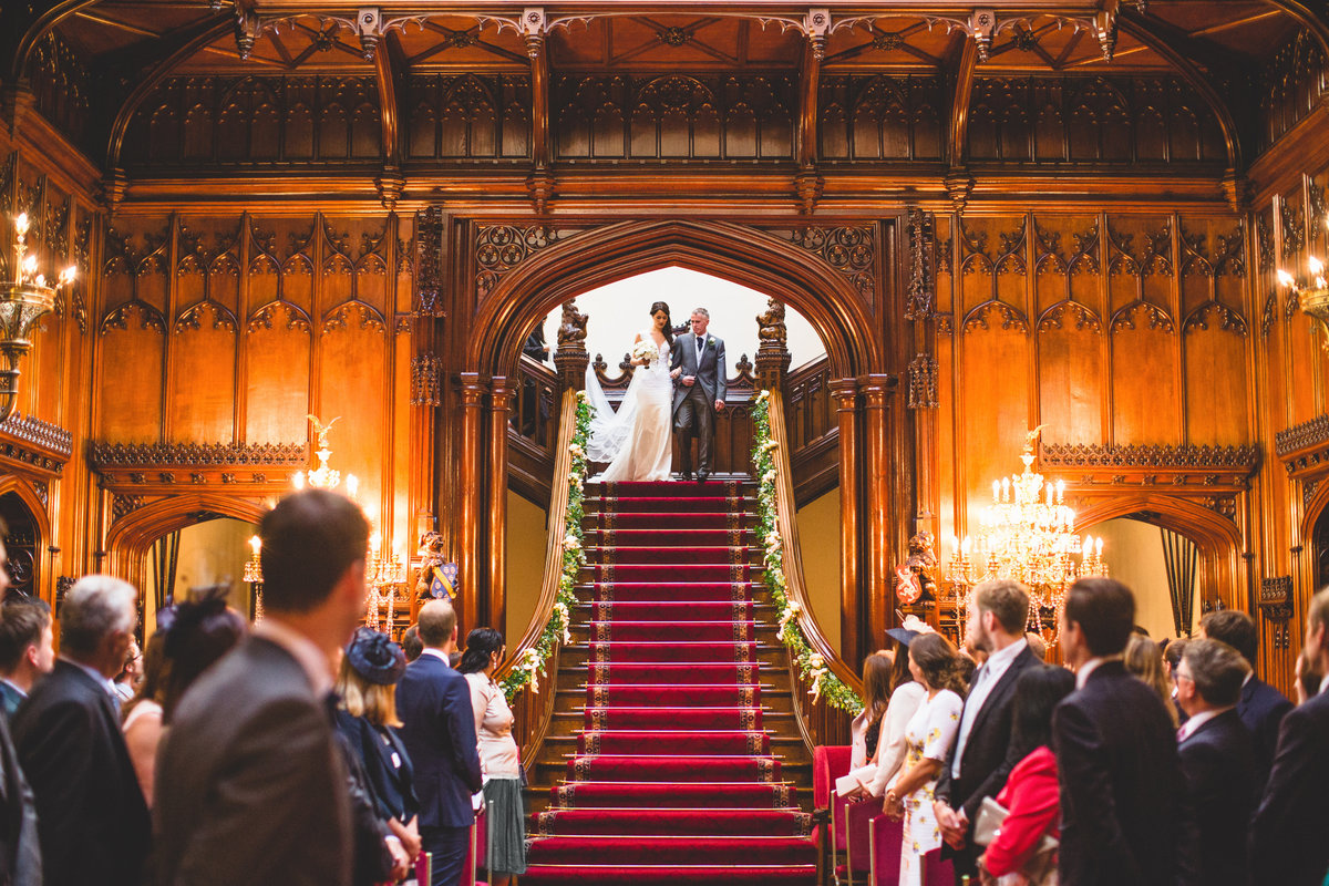 the bride and her father walk down the stairs at allerton castle