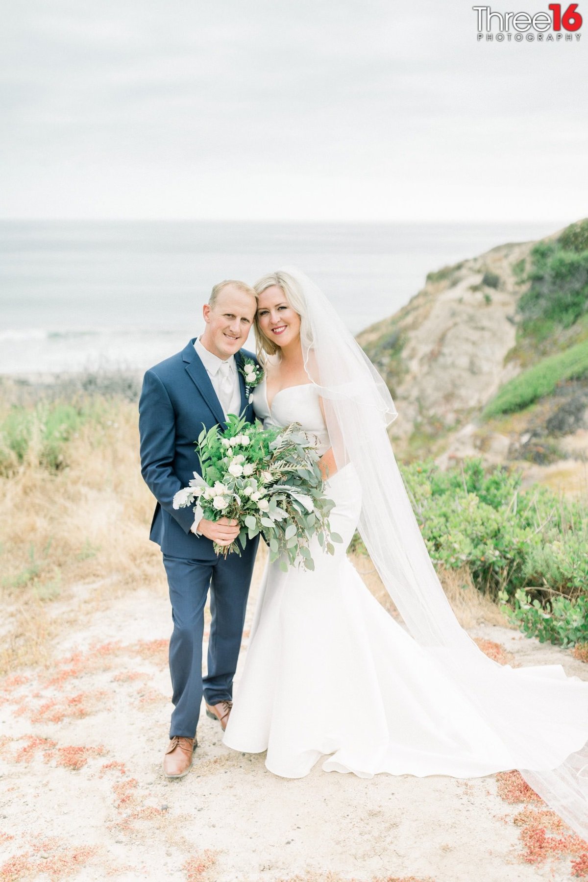 Bride and Groom pose for photos on the beach leading to the ocean in San Clemente, CA