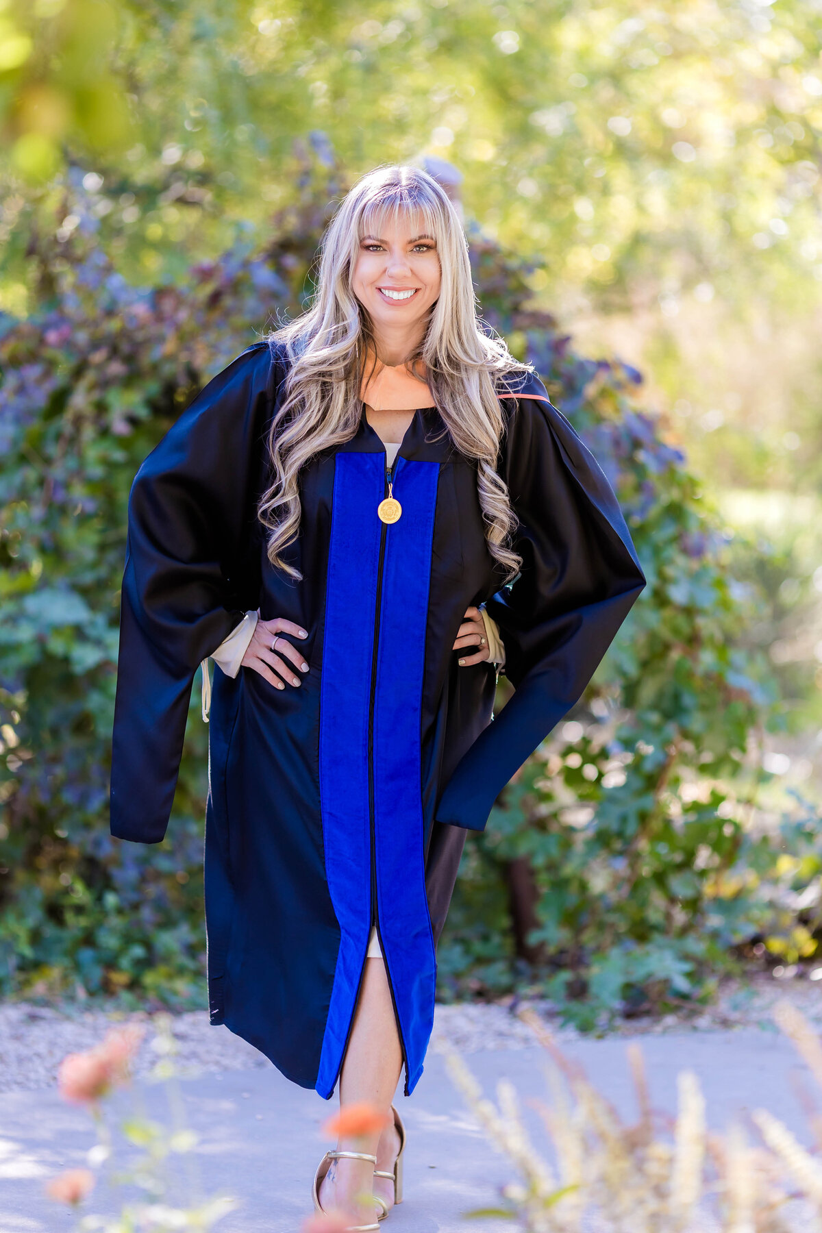 Woman UTA graduate  standing with hands on hips  and smiling at the camera