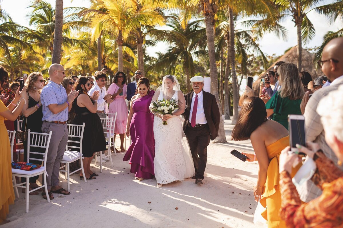 Bride walking down the aisle with parents at Grand Palladium Colonial Resort, Riviera Maya beach wedding