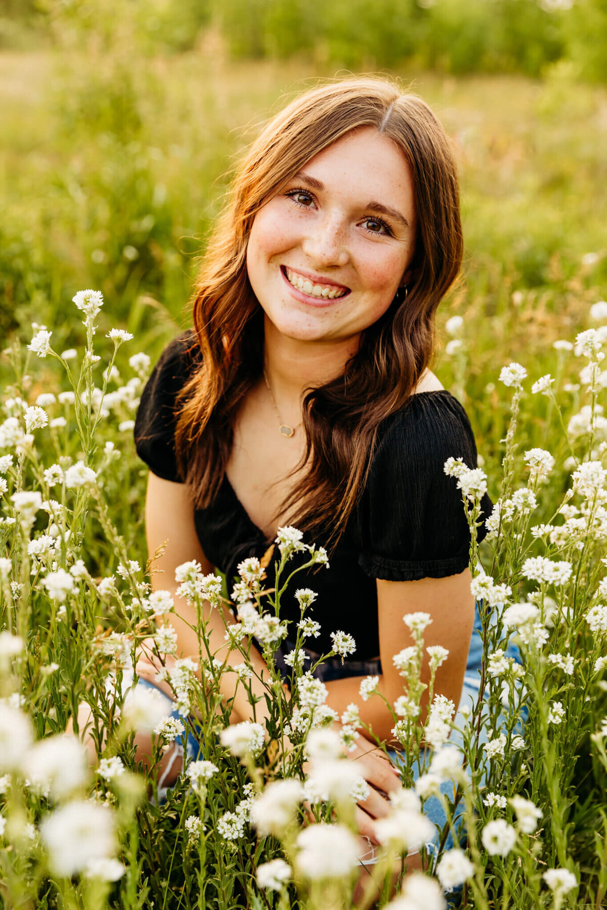beautiful high school girl sitting in a field of flowers by Ashley Kalbus Photography