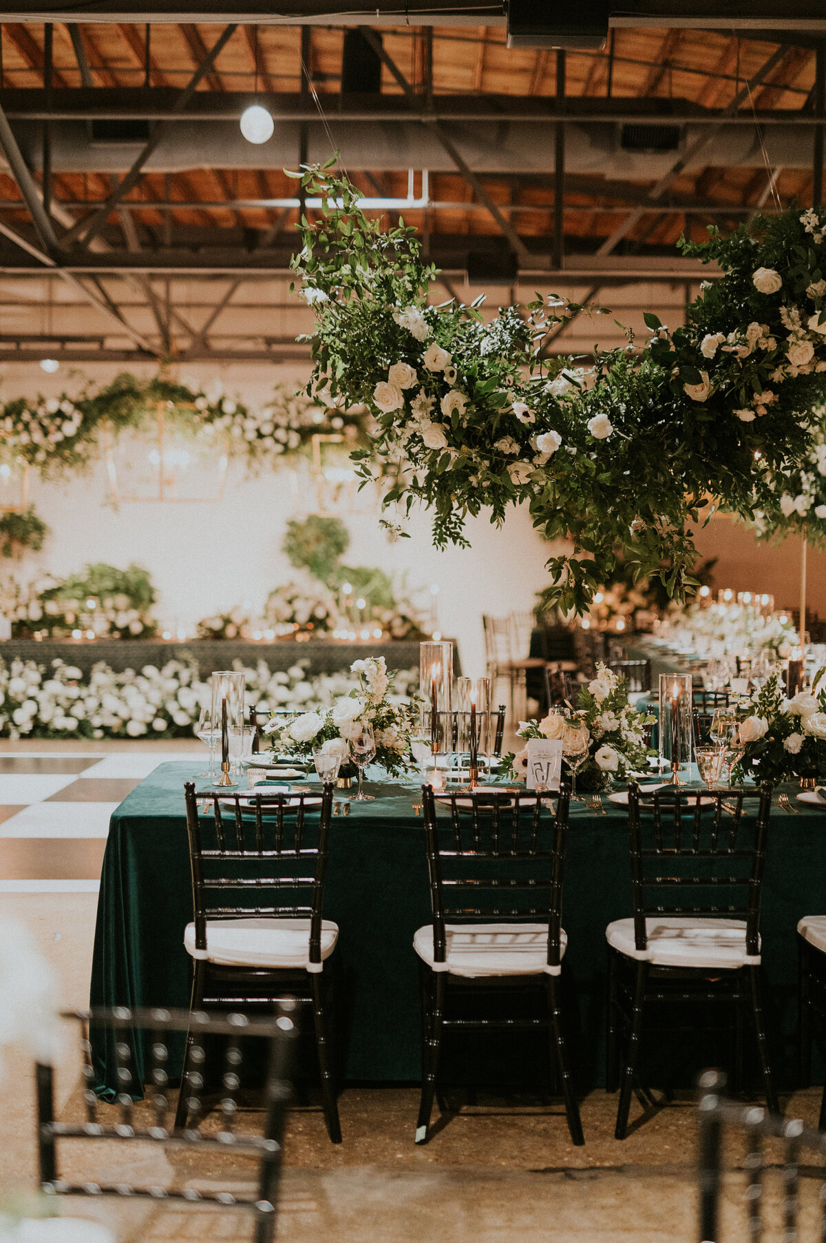 Eye-catching hanging floral installation decorate this winter wedding reception tables with floral hues of white, cream, black, and emerald composed of petal heavy roses, anemones, delphinium, carnations, and natural greenery. Design by Rosemary and Finch in Nashville, TN.