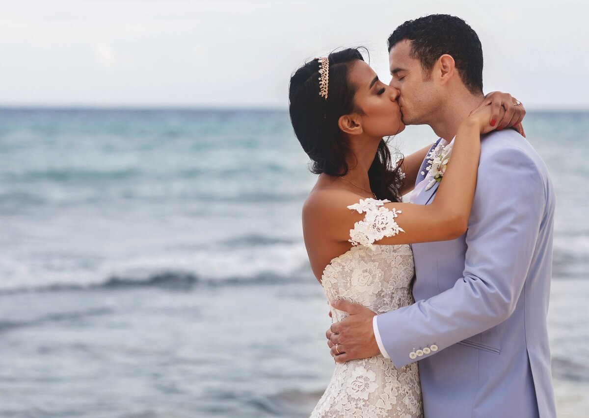 Bride and groom kissing on beach after wedding in Riviera Maya