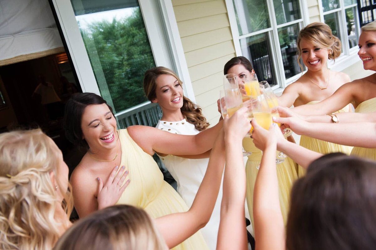 bridesmaids wearing yellow cheers with their mimosas