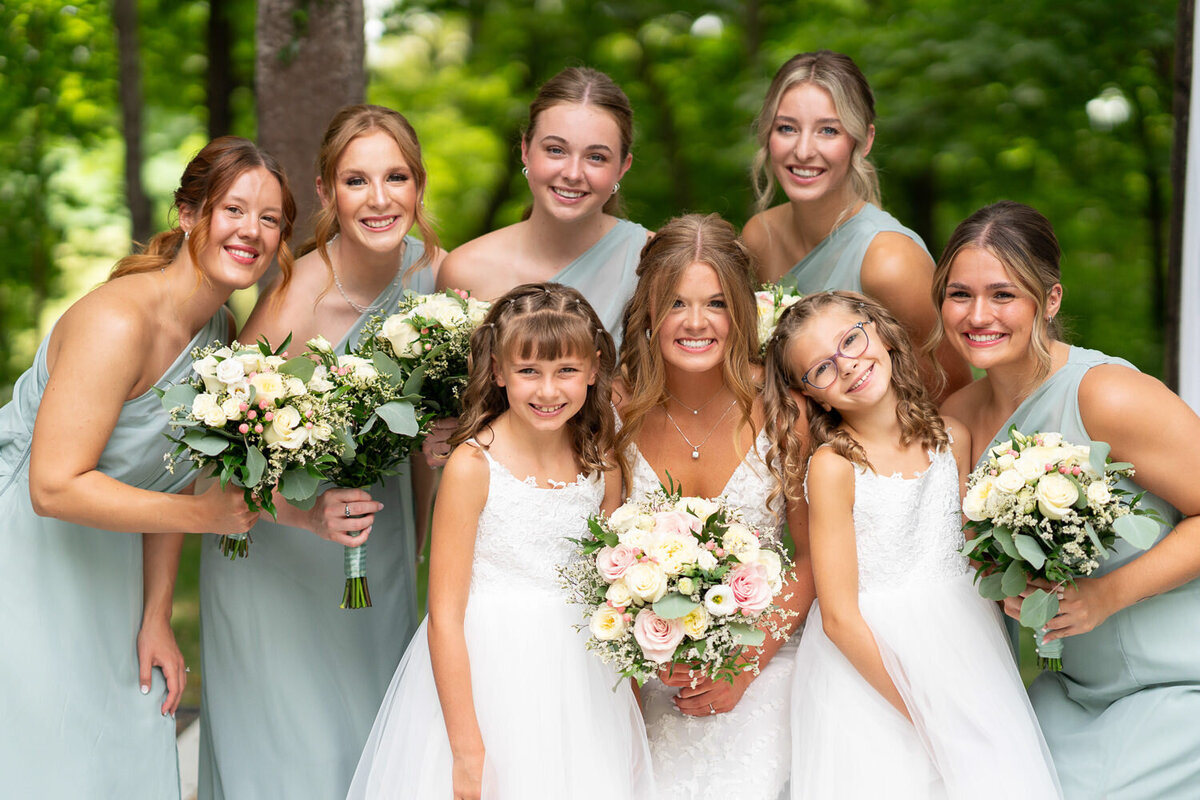 Bride smiles with bridesmaids and flower girls.