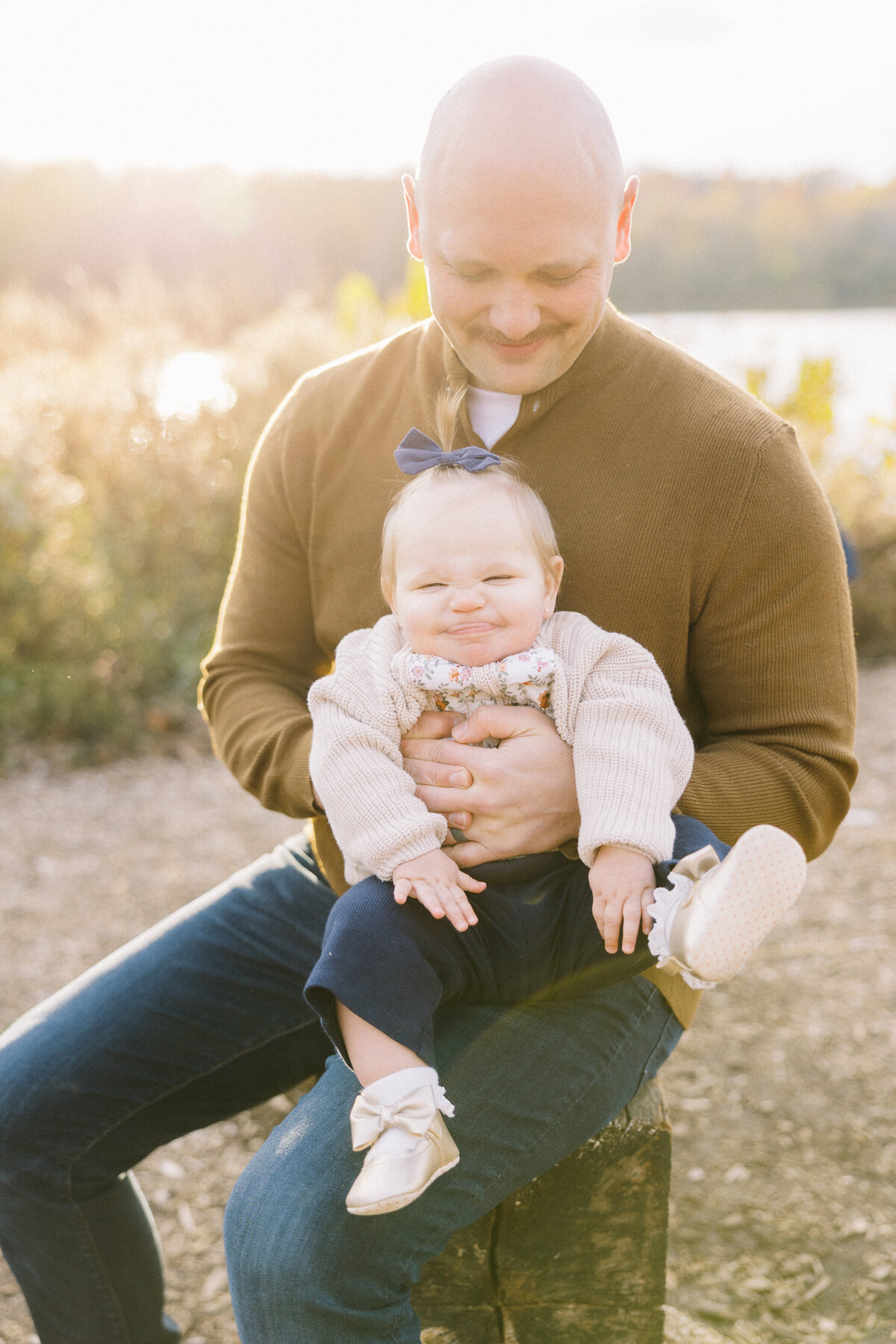 baby girl making a silly face while daddy holds her during sunset family photos
