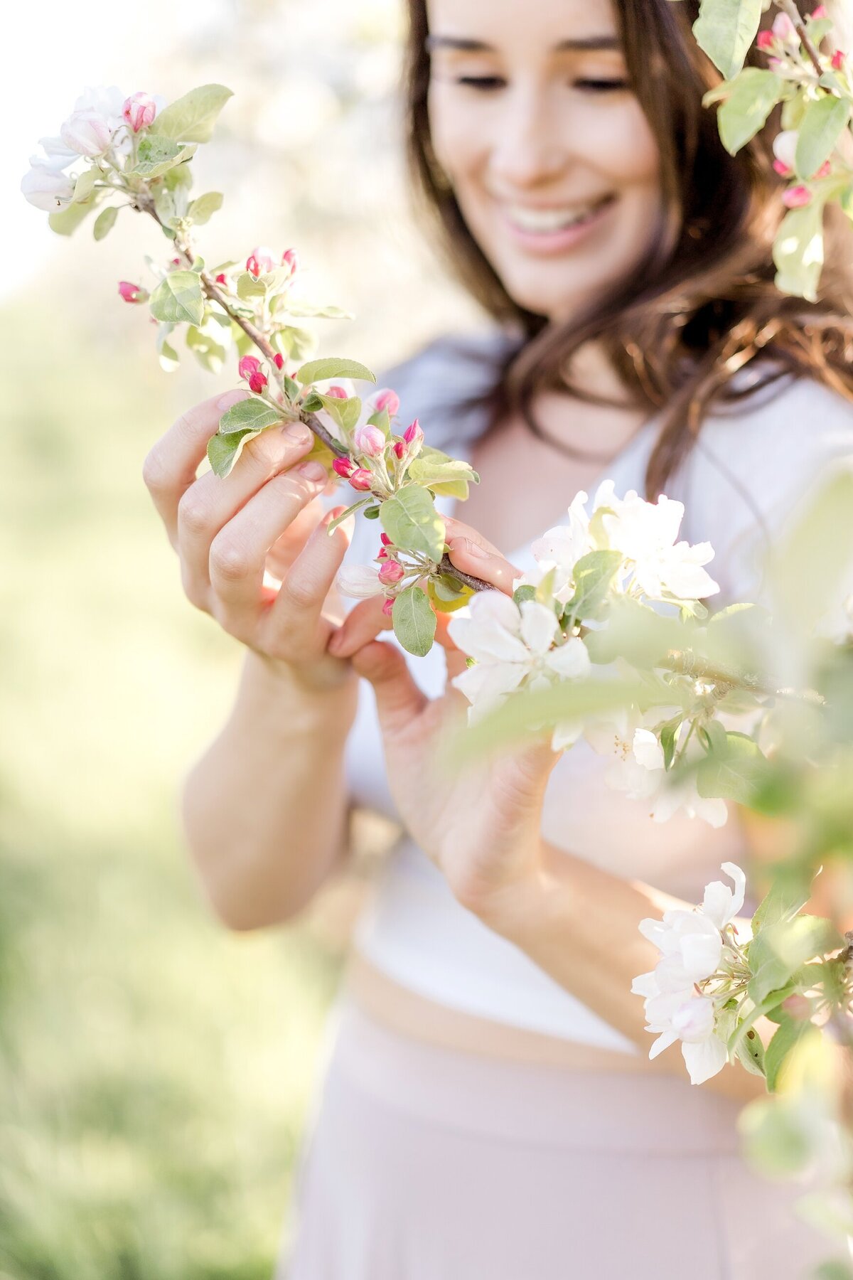 Woman holds branch of blooming flowers.
