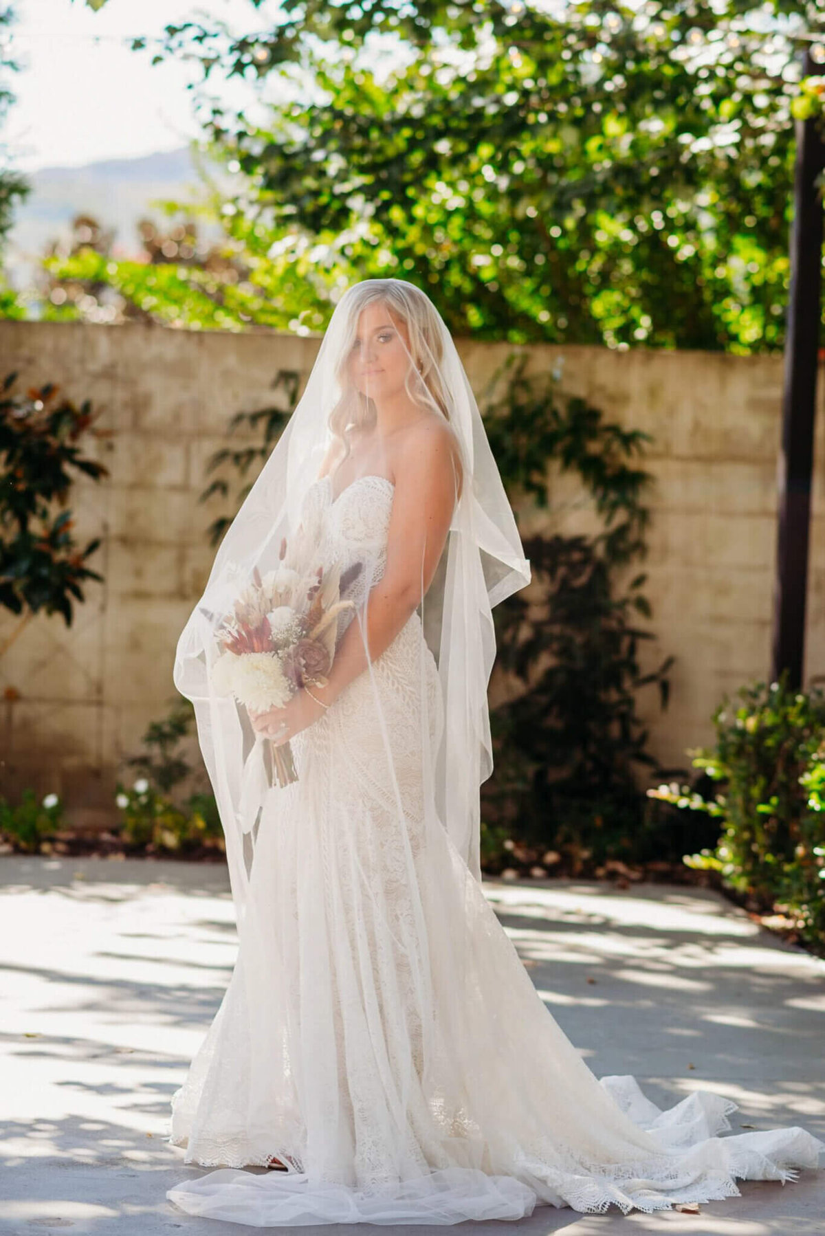 photo of a bride in front of a brick wall with a veil over her head