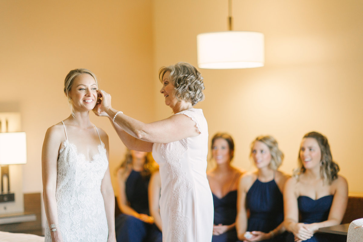 Mother of the bride helps daughter put on earrings prior to Firestone Winery wedding