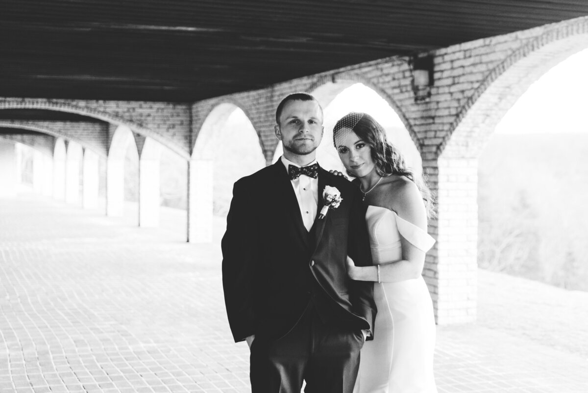 black and white image of bride holding onto groom and both more serious