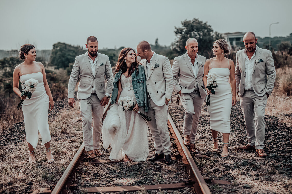 Newlywed couple's railway track pose with a soft-focus on friends