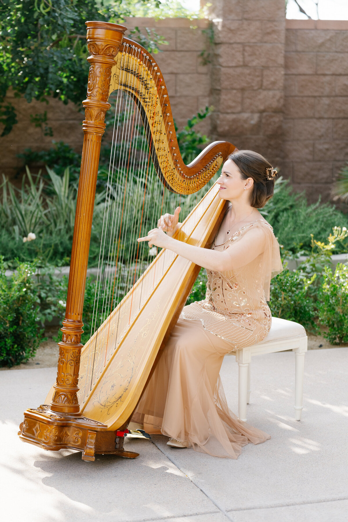 Kristie Smith, delivering an enchanting performance of harp wedding songs during a picturesque outdoor ceremony at DragonRidge Country Club.