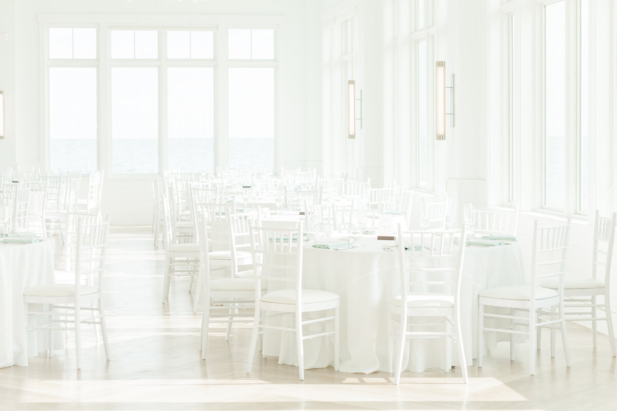 All white wedding reception featuring white walls, white chairs, white table linens at Wychmere Beach Club in Harwich Port MA. Captured by Lia Rose Weddings