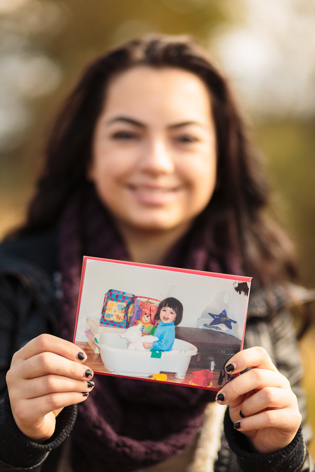Color image of girl holding a picture of herself as a child
