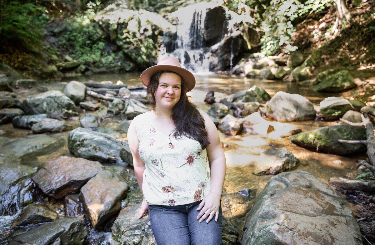 A therapist who runs a small business poses in front of a waterfall during her personal branding photos.