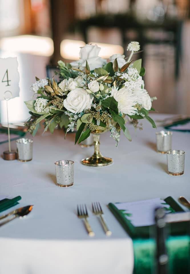 Gold compote with lush white flowers and greenery accented with small  gold mercury votives