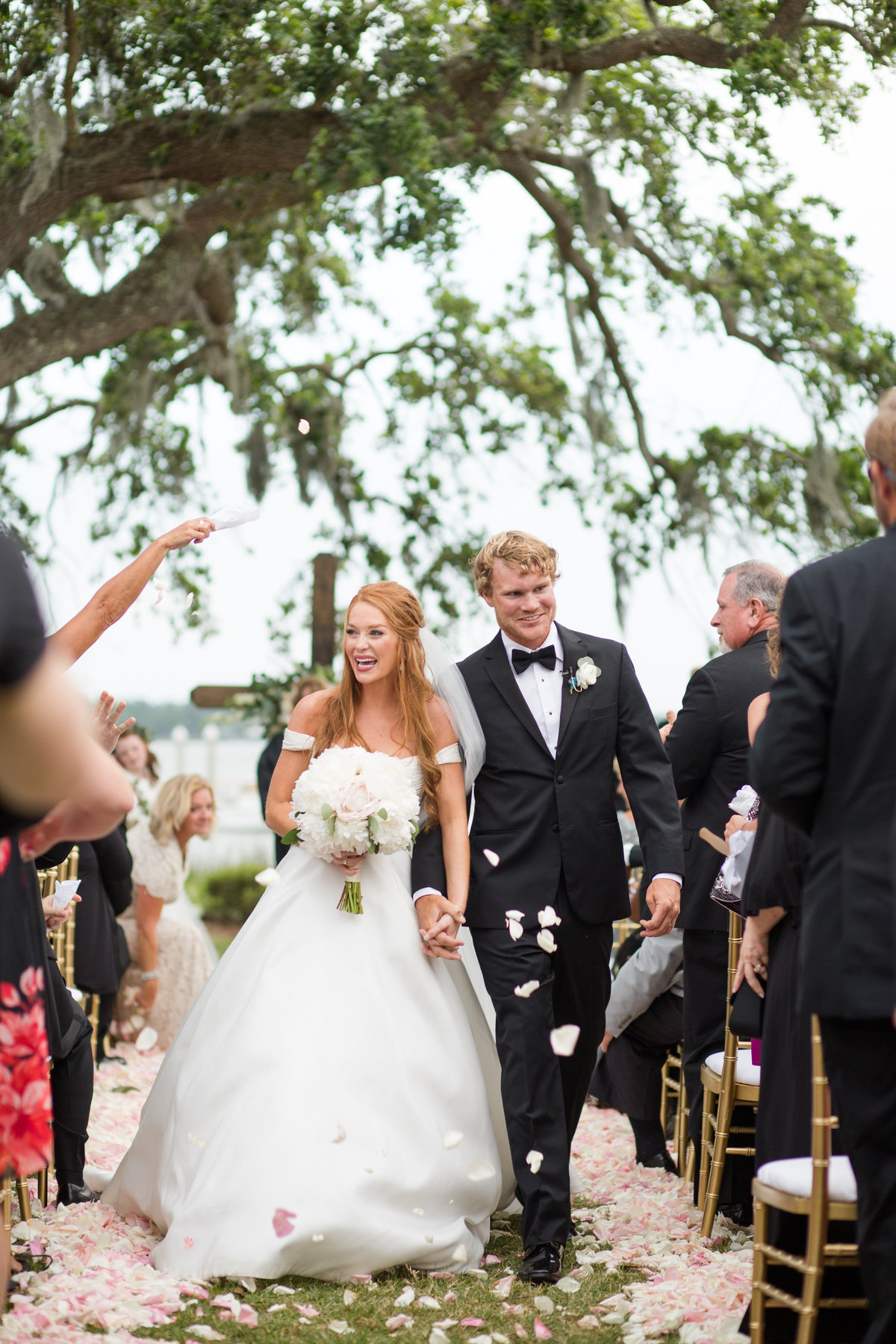 bride and groom walking down aisle with rose petals thrown at them. savannah yacht club wedding.