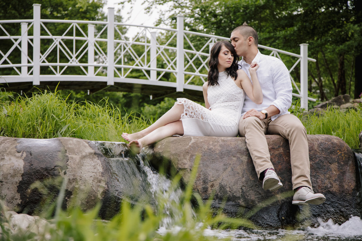 engaged couple sits by stream at sayen gardens