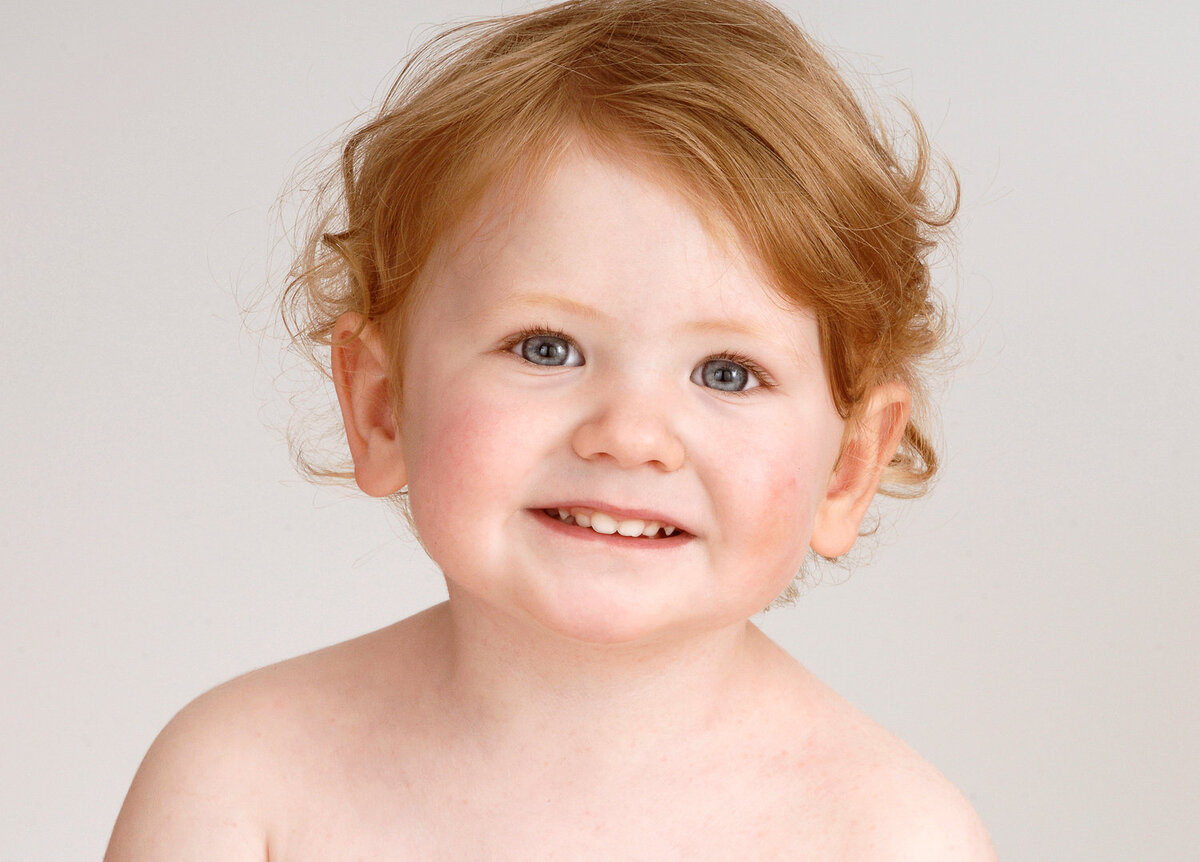 toddler with light brown hair smiling in studio