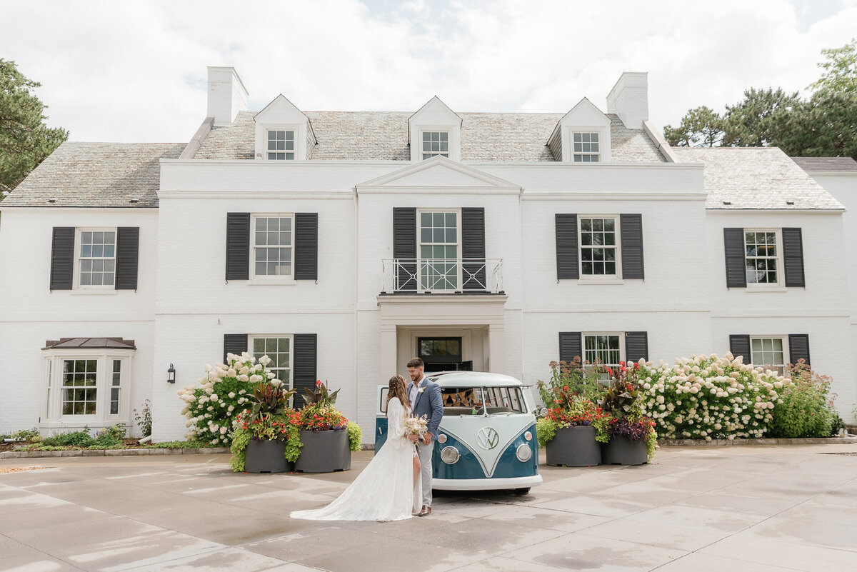 Bride and groom with their vintage VW bus in from of their wedding venue