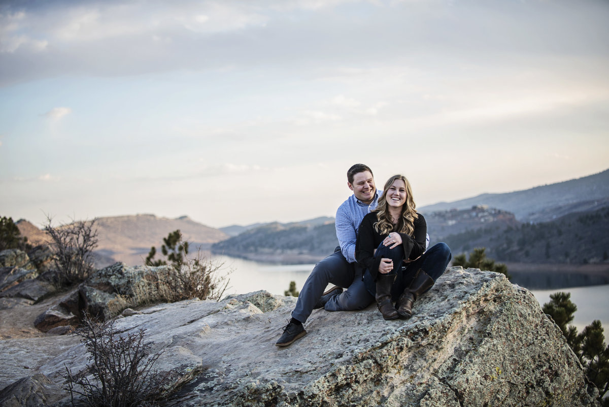 Couple cuddling on a rock with mountain views