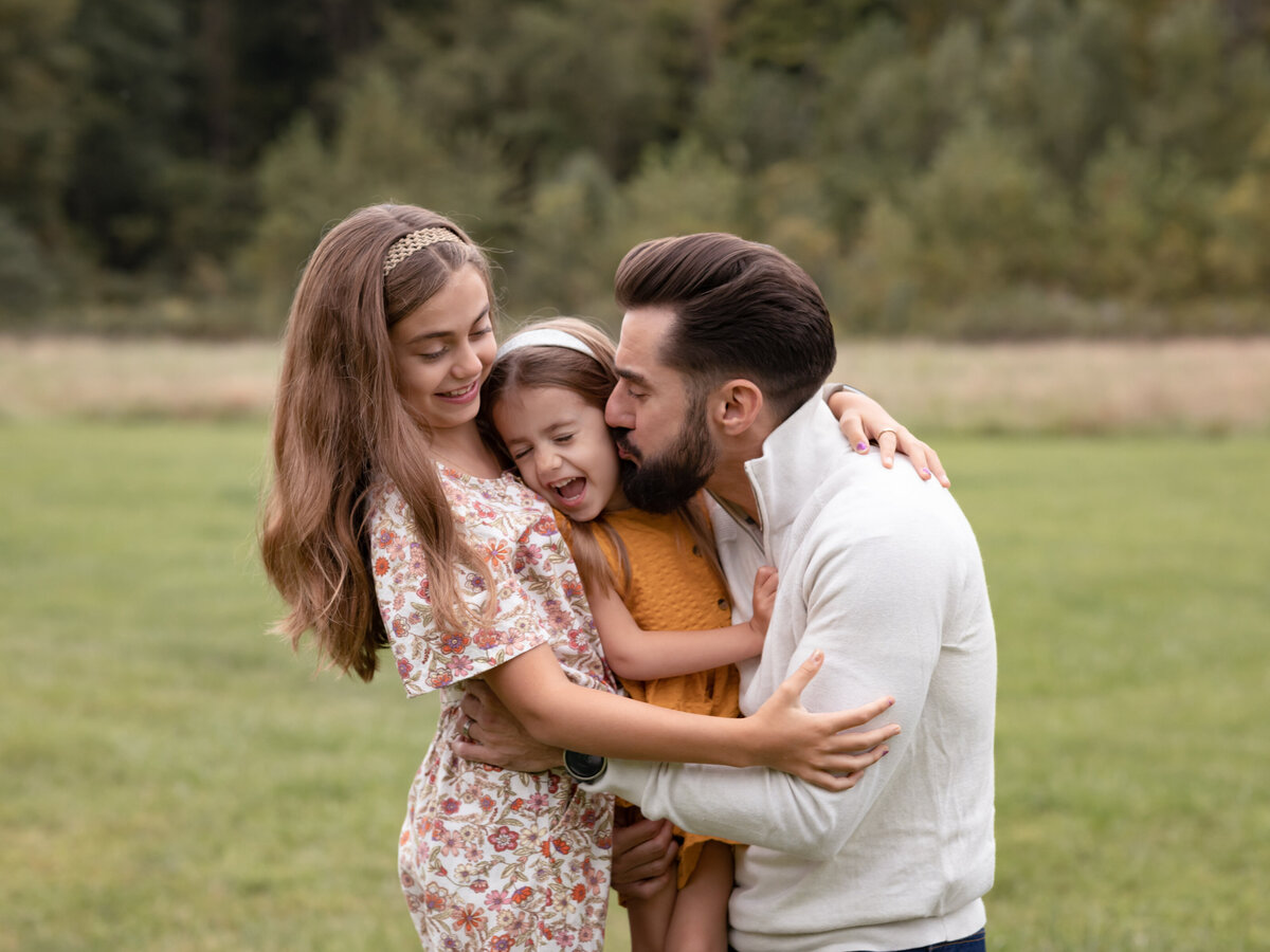 dad hugging daughters for family photos