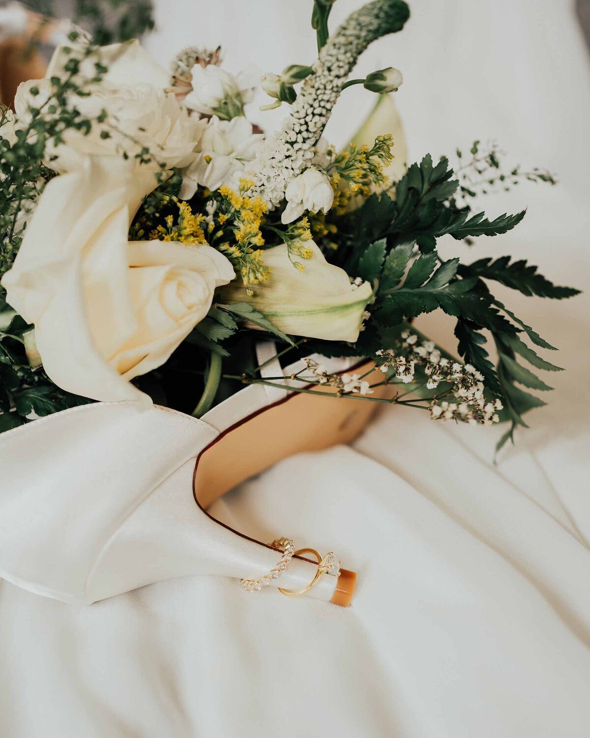 Maddie Rae Photography detail shot of the brides flowers, rings, and shoe. the rings are on the heel of the shoe