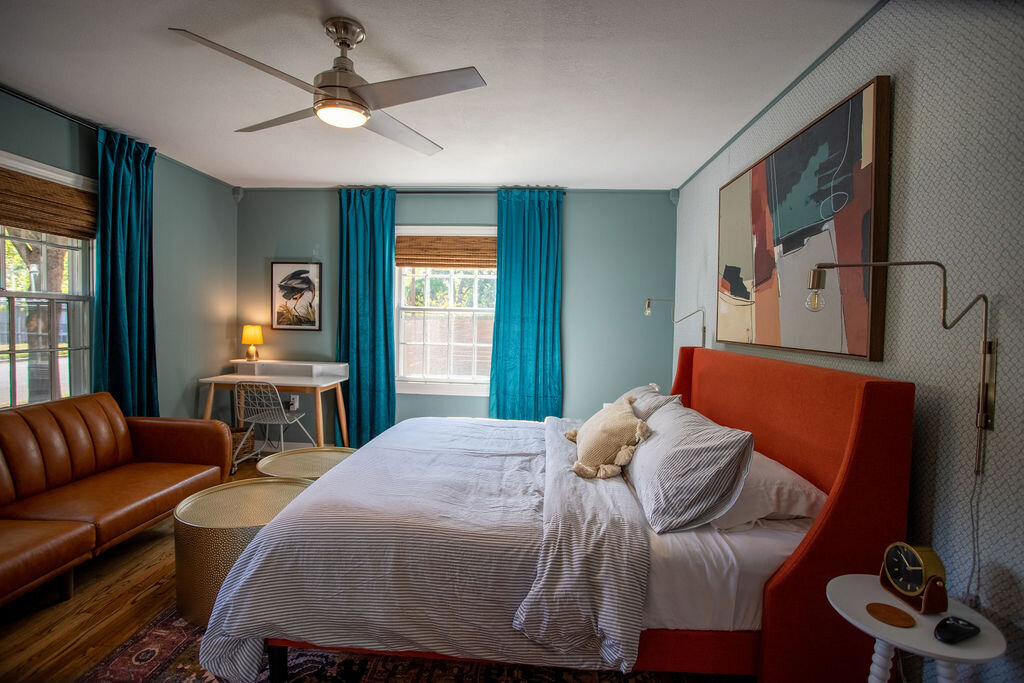 Large bed with plush bedding in this three-bedroom, two-bathroom mid-century house that sleeps 8 and boasts a unique experience in color, style, and lifestyle products located in the heart of Waco, TX.