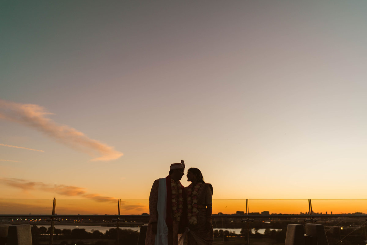 Indian bride and groom standing on rooftop of the Intercontinental wharf at sunset