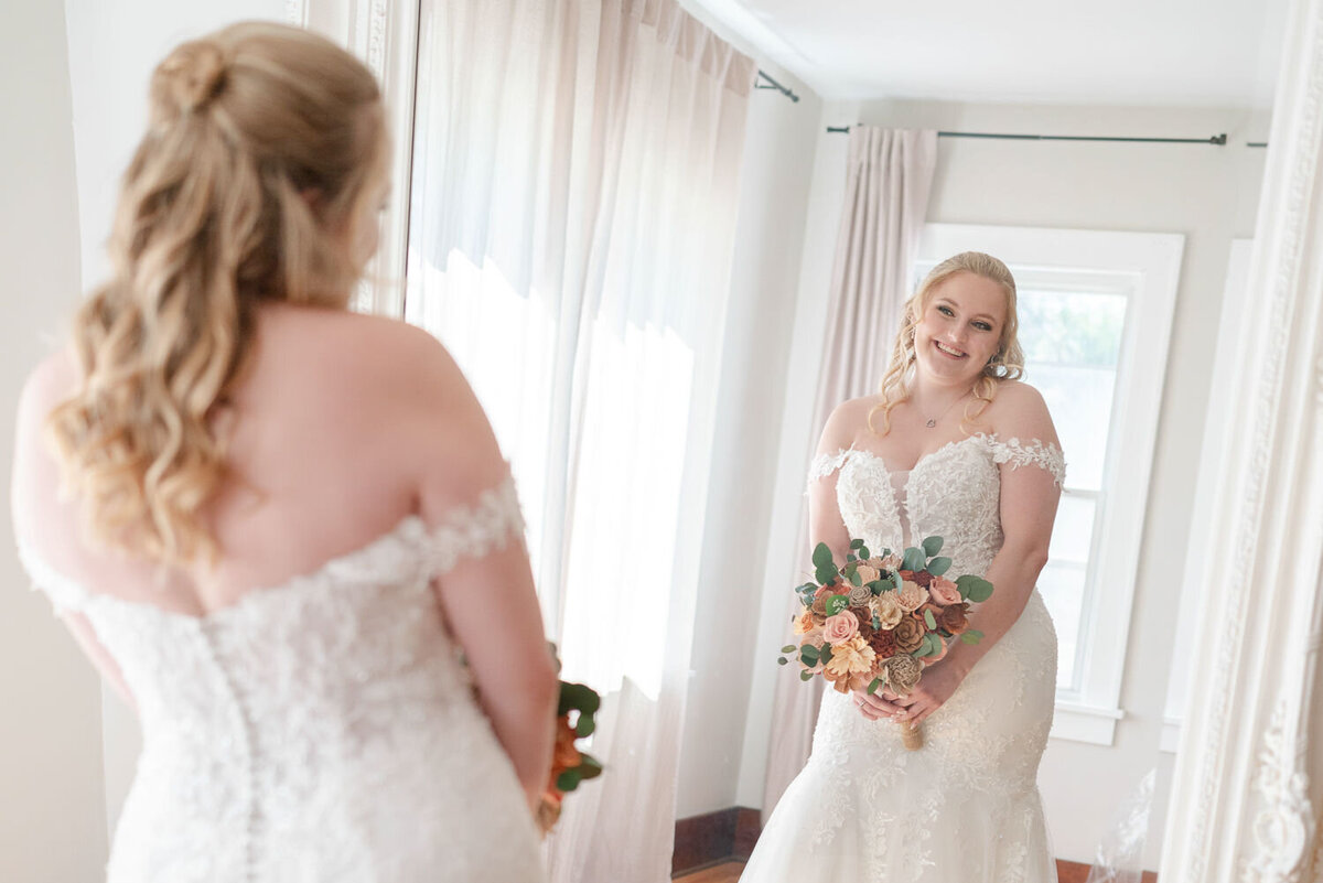 Bride smiles at herself in the mirror.