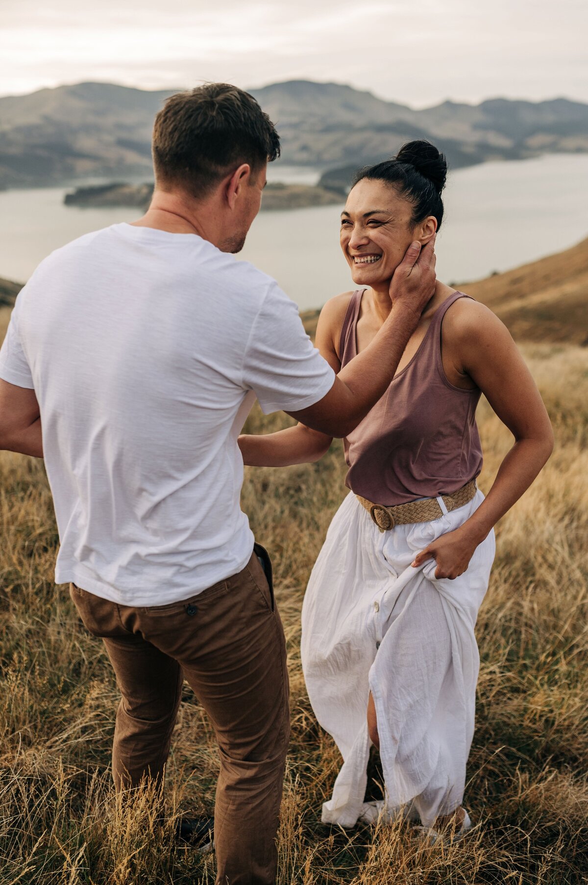 couple port hills christchurch sunrise engagement shoot pink white shirt holding face in love smiling young