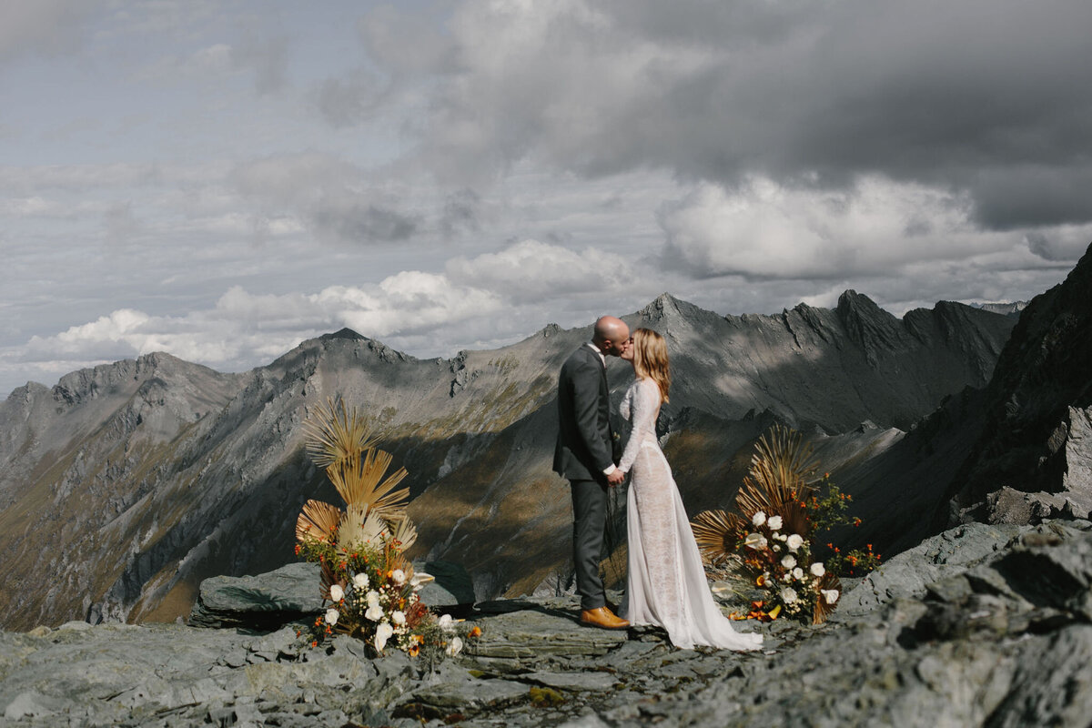 The Vase Floral Co - wedding on top of mountain in Queenstown New Zealand - standing flower arrangments frame with bride and groom