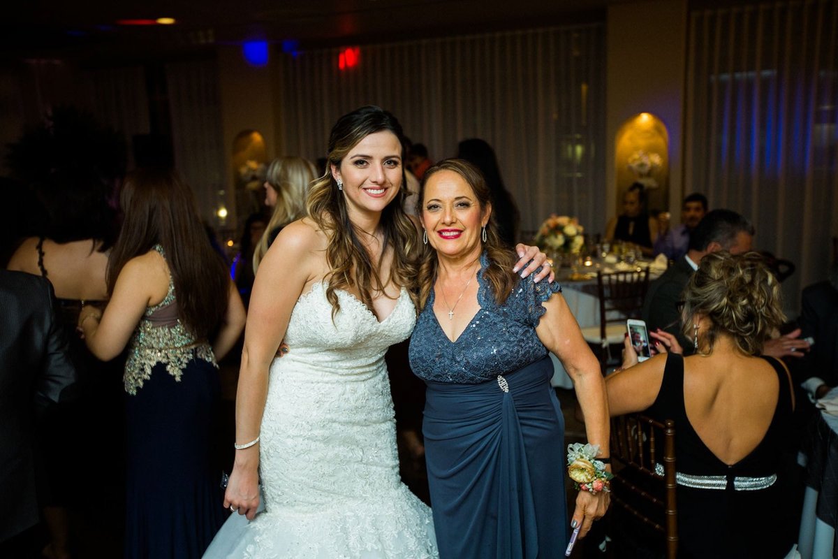 Bride poses with her mother at the wedding reception