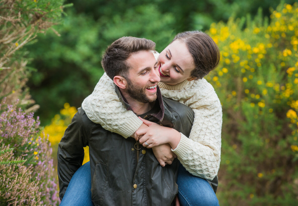 Young couple in wax jacket and aran sweater having fun and surrounded by flowers