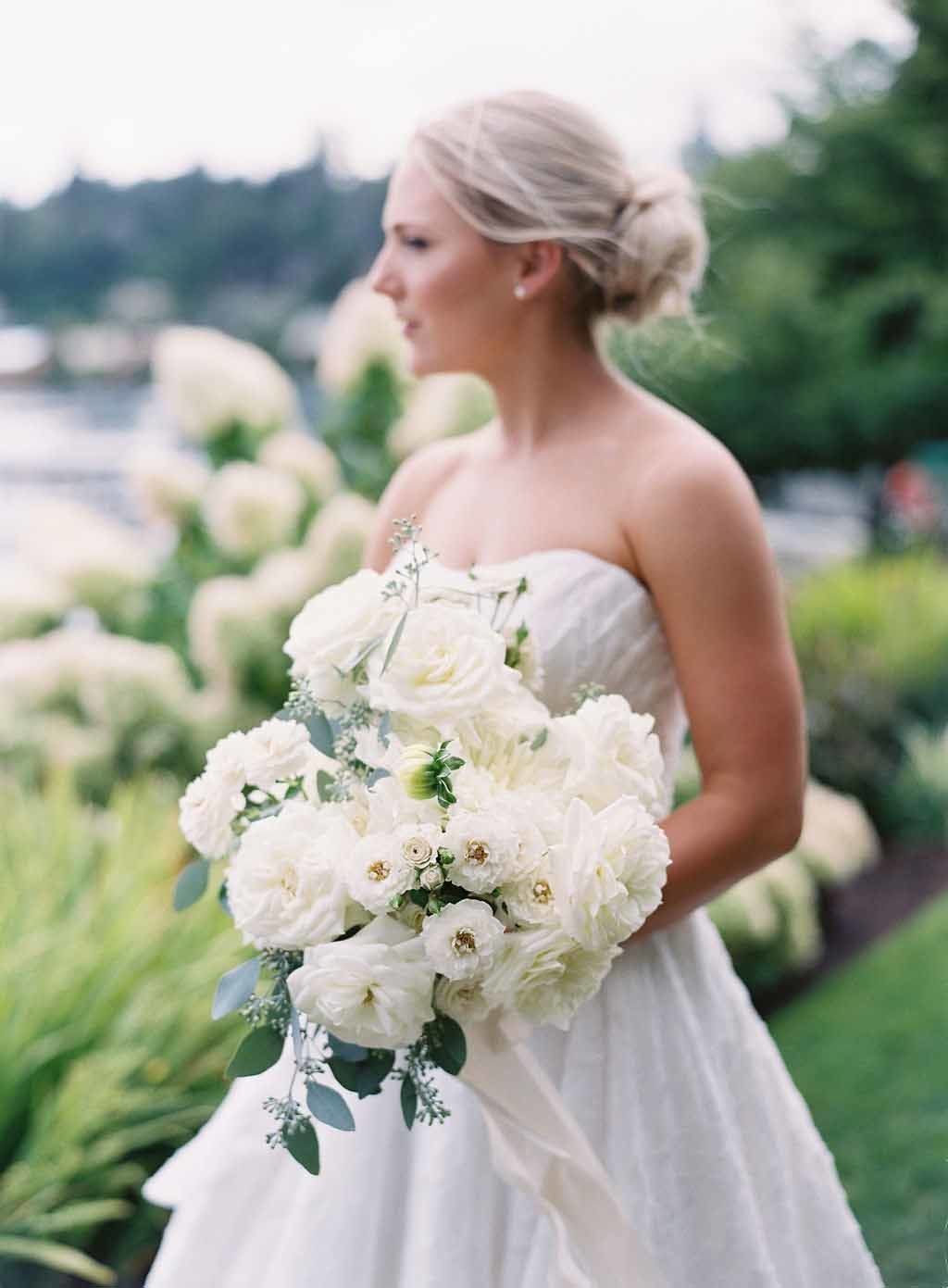 bride with all white bouquet of roses, dahlias, garden roses standing in Seattle Tennis club garden