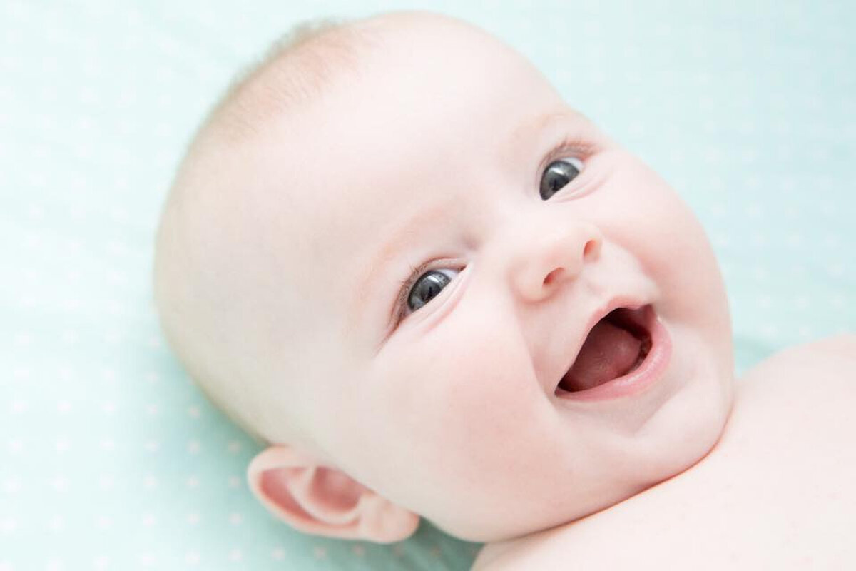 A bald white baby grins at the camera Rockland County newborn photographer Milestone Images