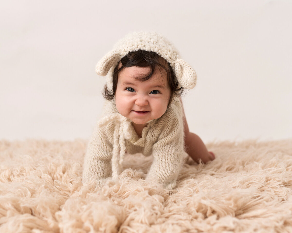 Smiling baby in a cream furry background by Laura King Photography