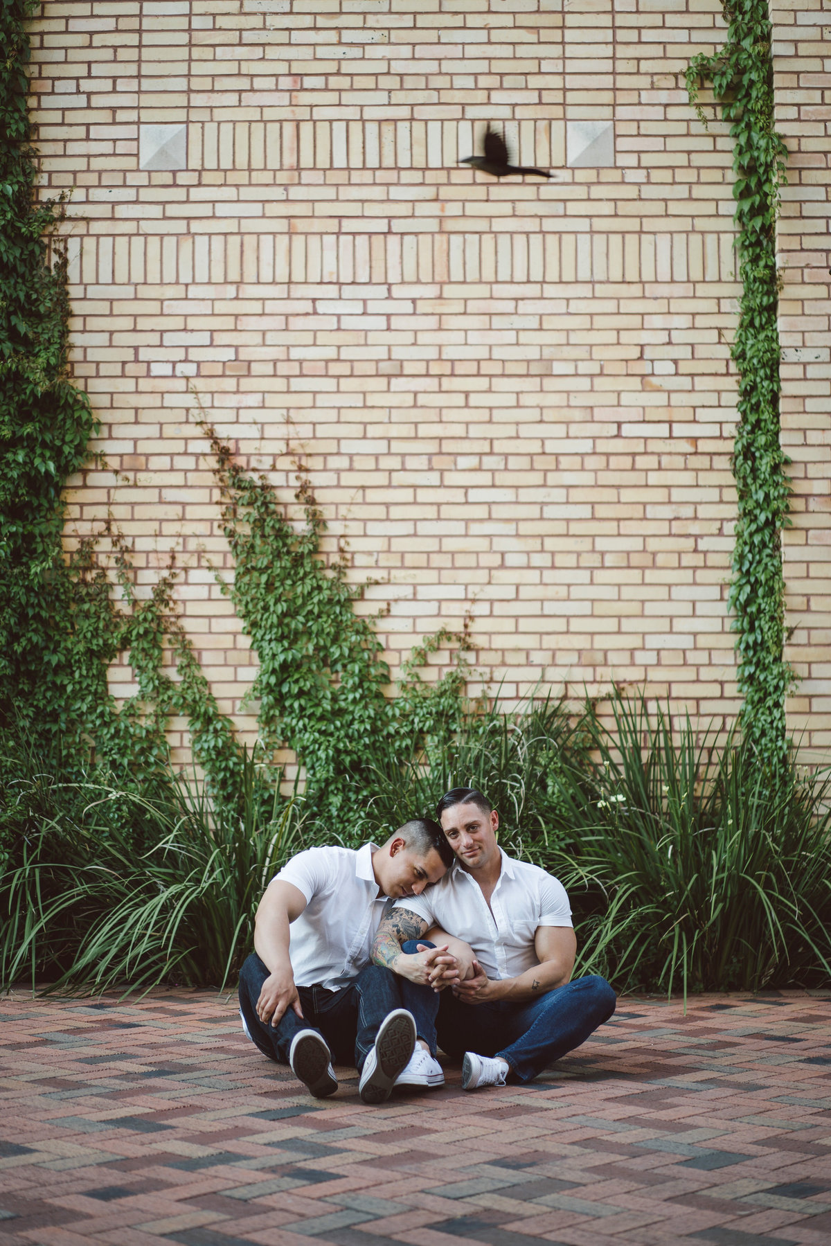 Engaged couple, two men holding each other while sitting on the floor at the Historic Pearl. Same sex engagement session.