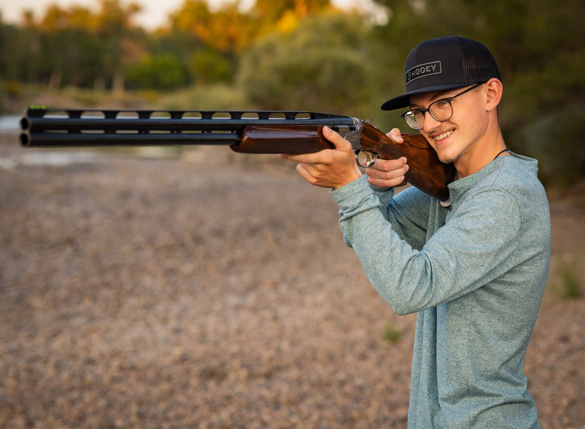 teenage boy holding his  equipment for skeet shooting