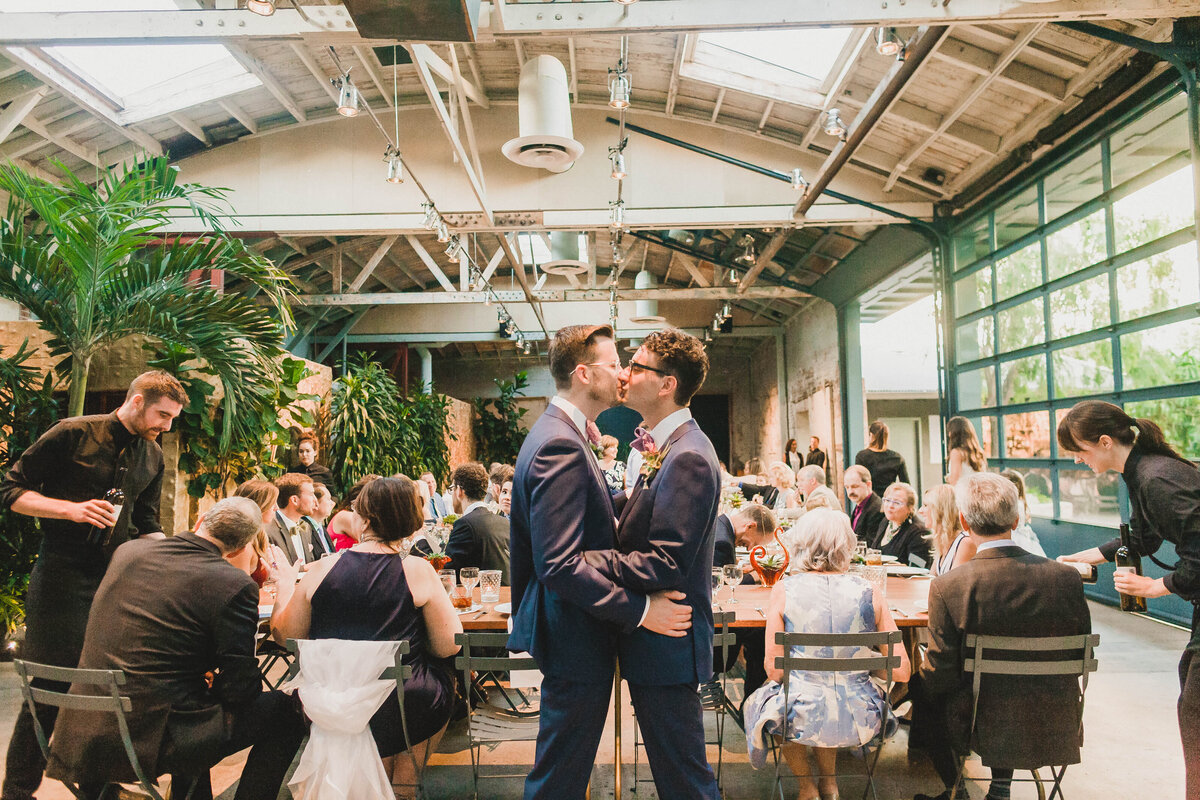 Gay couple kisses at their wedding reception