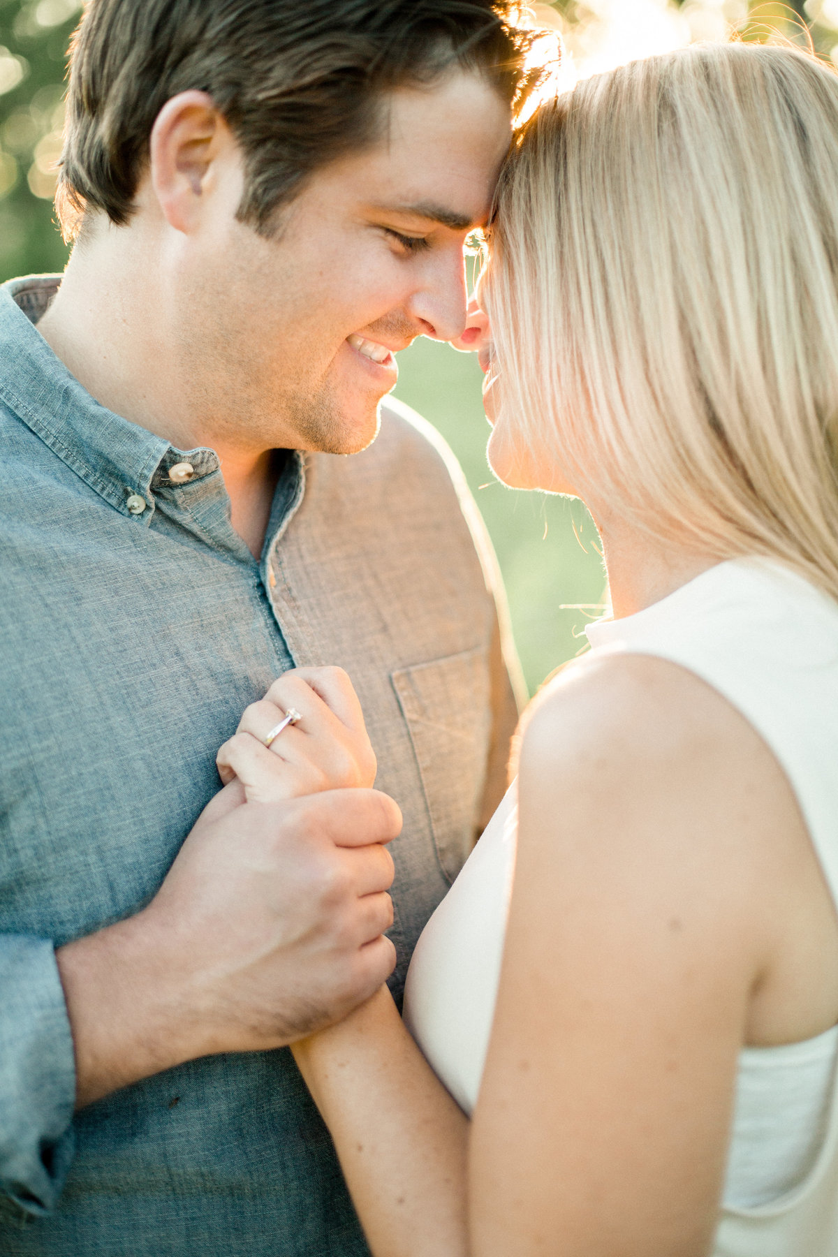 forehead to forehead pose holding hands in summer light engagement photography minnesota