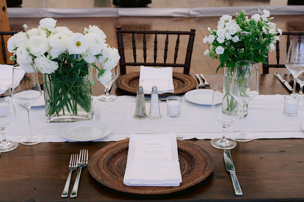 A dining table set-up with white flower centerpieces and cutleries for a wedding at Cape Cod Summer Tent, MA.
