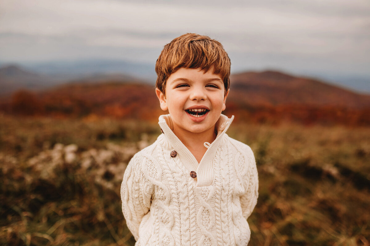 Little boy laughs for photos during Family Photoshoot at Max Patch in Asheville, NC.