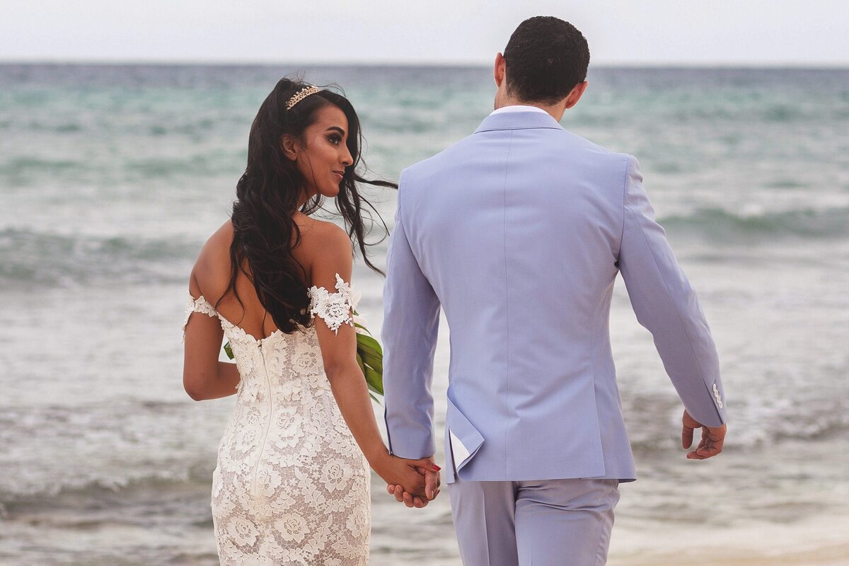 Bride and groom walk on beach in Riviera Maya