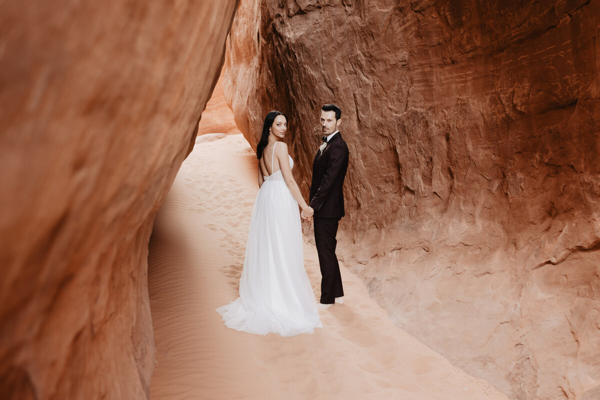 Utah elopement photographer captures couple walking hand in hand through Arches