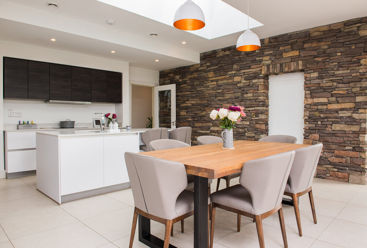 Modern kitchen with white gloss units and exposed stone walls