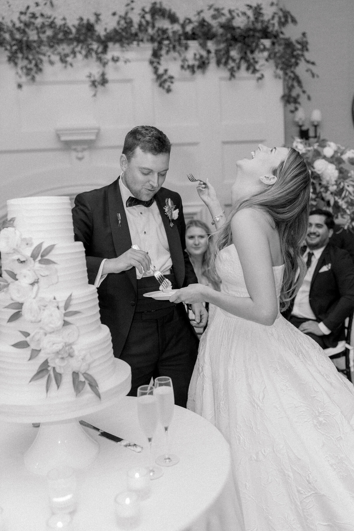 Bride laughs after groom feeds her a piece of cake. Fun and sentimental black and white wedding day photos. Kailee DiMeglio Photography. Kiawah River Course wedding.