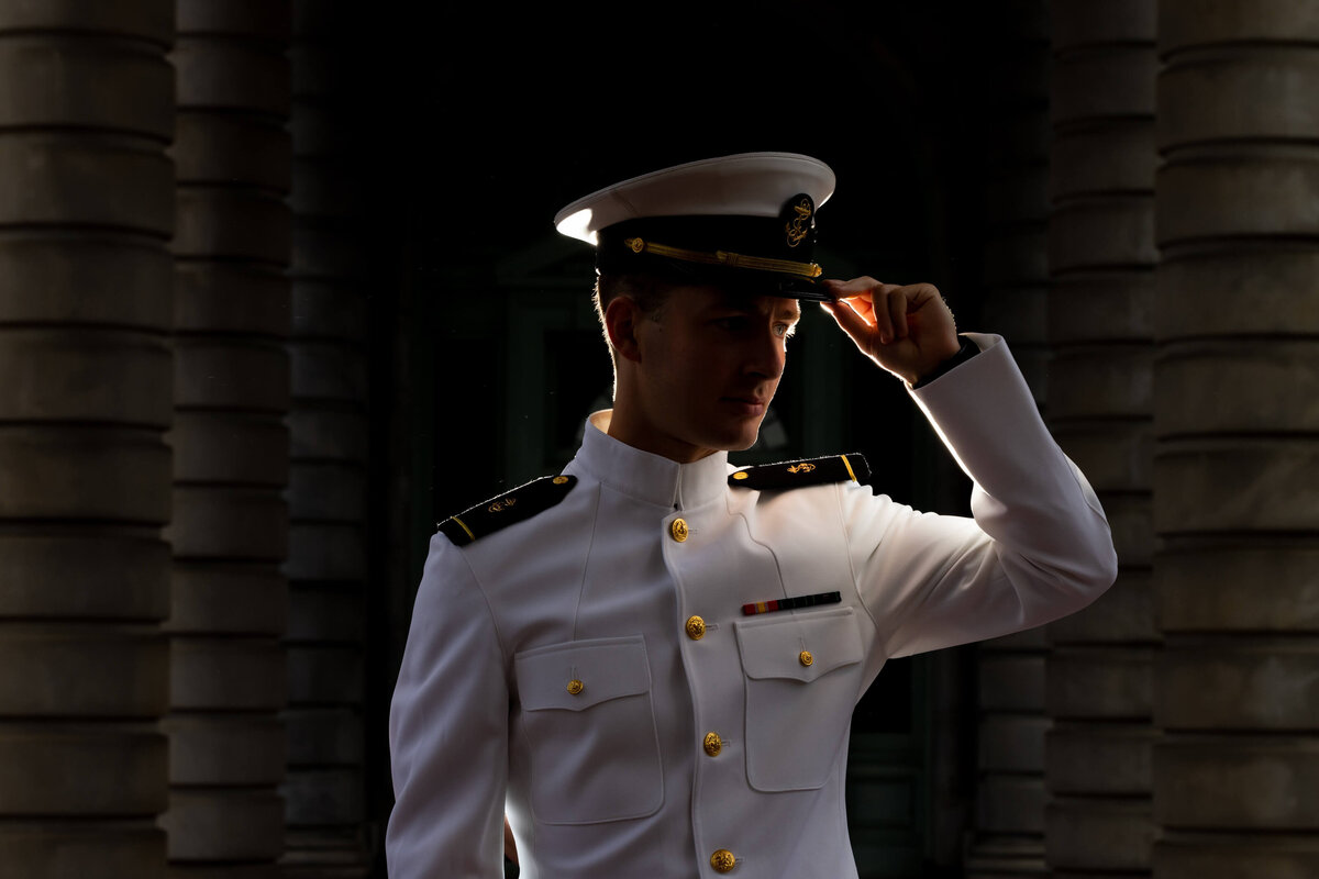 Dramatic backlit portrait of Naval Academy officer in white uniform.